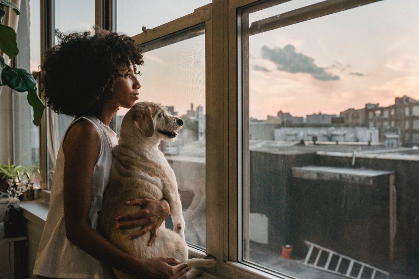woman holding dog looking out window